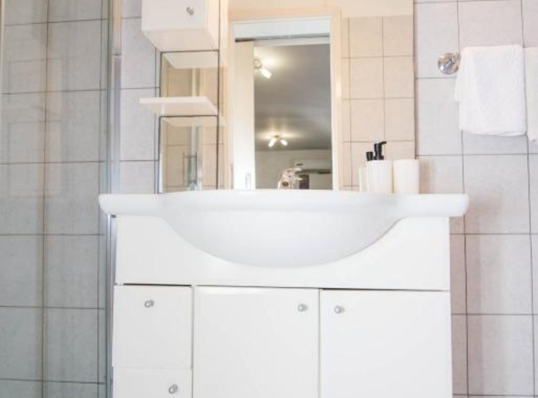 Un baño moderno con un tocador blanco, un espejo y una toalla colgada en la pared.