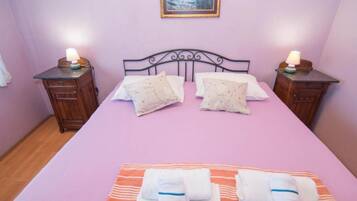 Un dormitorio con una cama, dos mesitas de noche, un cuadro en la pared y toallas sobre la cama.