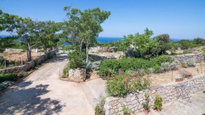 A pathway leading through a garden with stone walls and trees, overlooking a coastal area. - Apartments Bonic - Two Bedroom Apartment (Veli Losinj)