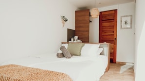 A modern bedroom with a large bed, a wooden wardrobe, a small bedside table, and a hanging light fixture. - Mata e' Platano Guesthouse #4, Luquillo PR (Luquillo)