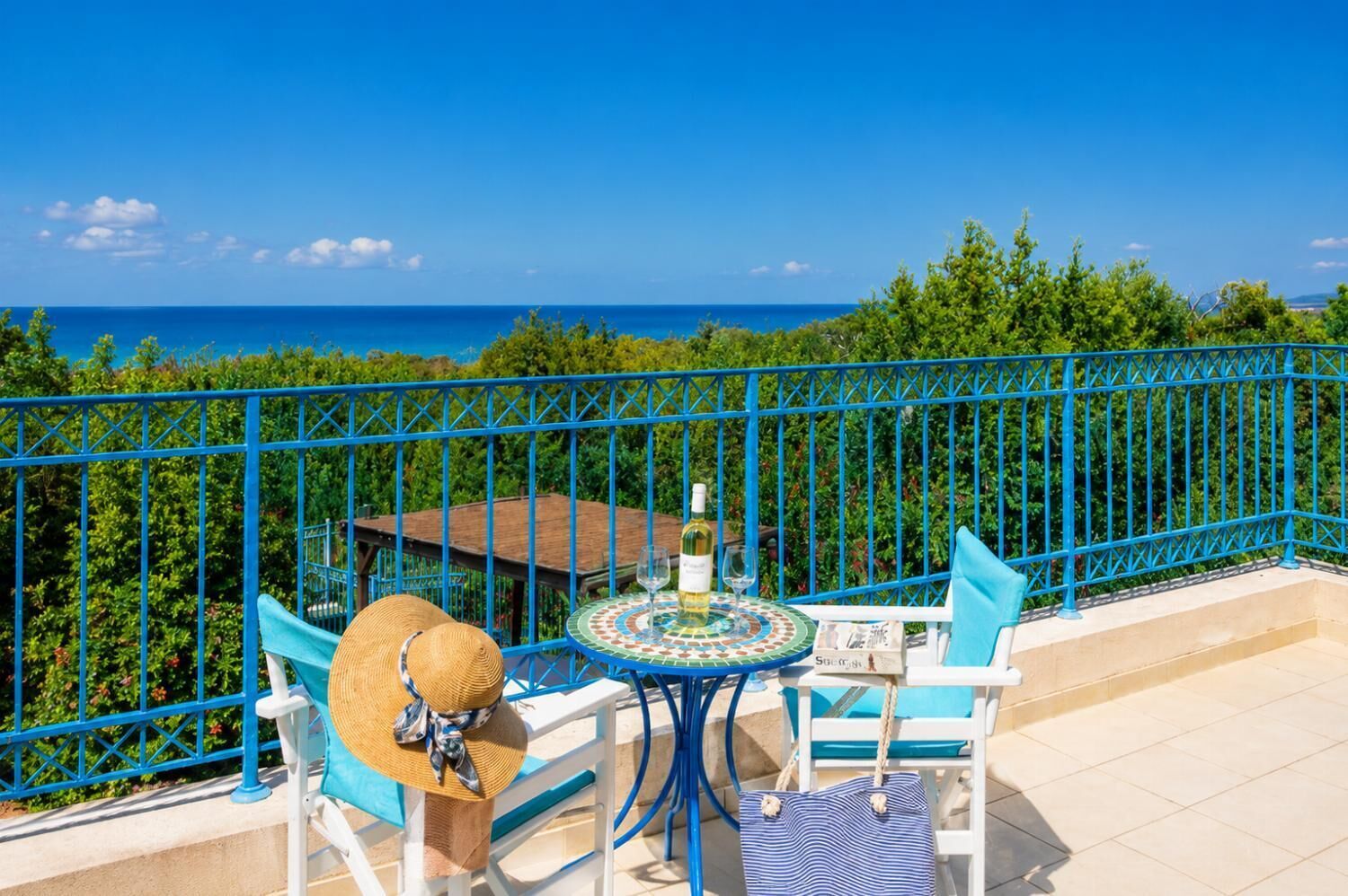 A balcony with a table, chairs, a bottle, and a glass.