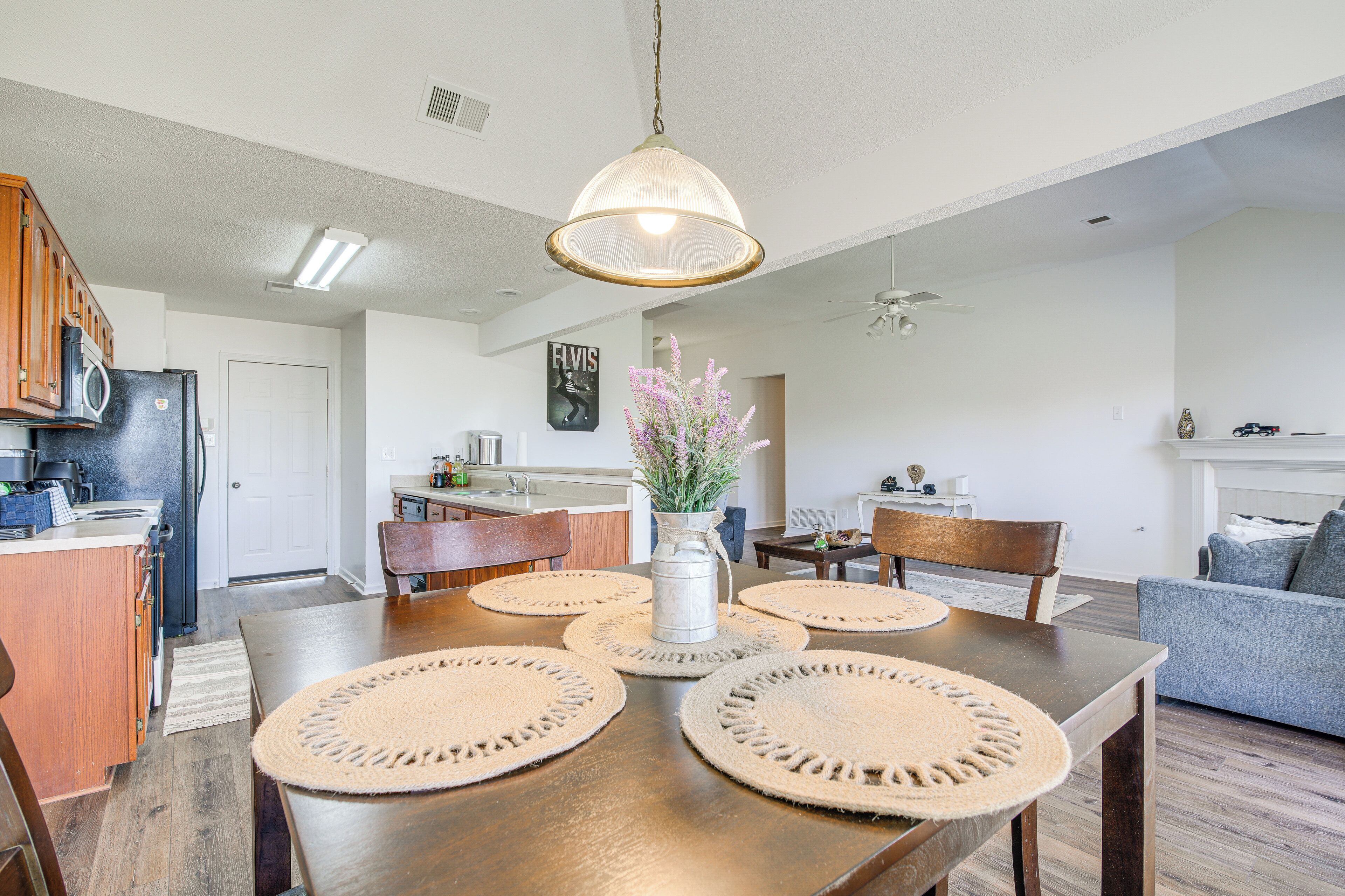 Une cuisine moderne avec des meubles en bois, un réfrigérateur et un coin repas comprenant une table en bois et des sets de table en fibres tressées.