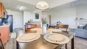 Una cocina moderna con armarios de madera, un refrigerador y un comedor con una mesa de madera y protectores de mesa tejidos.
