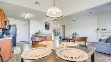 Une cuisine moderne avec des meubles en bois, un réfrigérateur et un coin repas comprenant une table en bois et des sets de table en fibres tressées.
