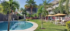 A pool surrounded by palm trees and a building with balconies.