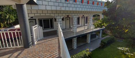 A multi-story building with a balcony, a tiled roof, and a well-maintained lawn.