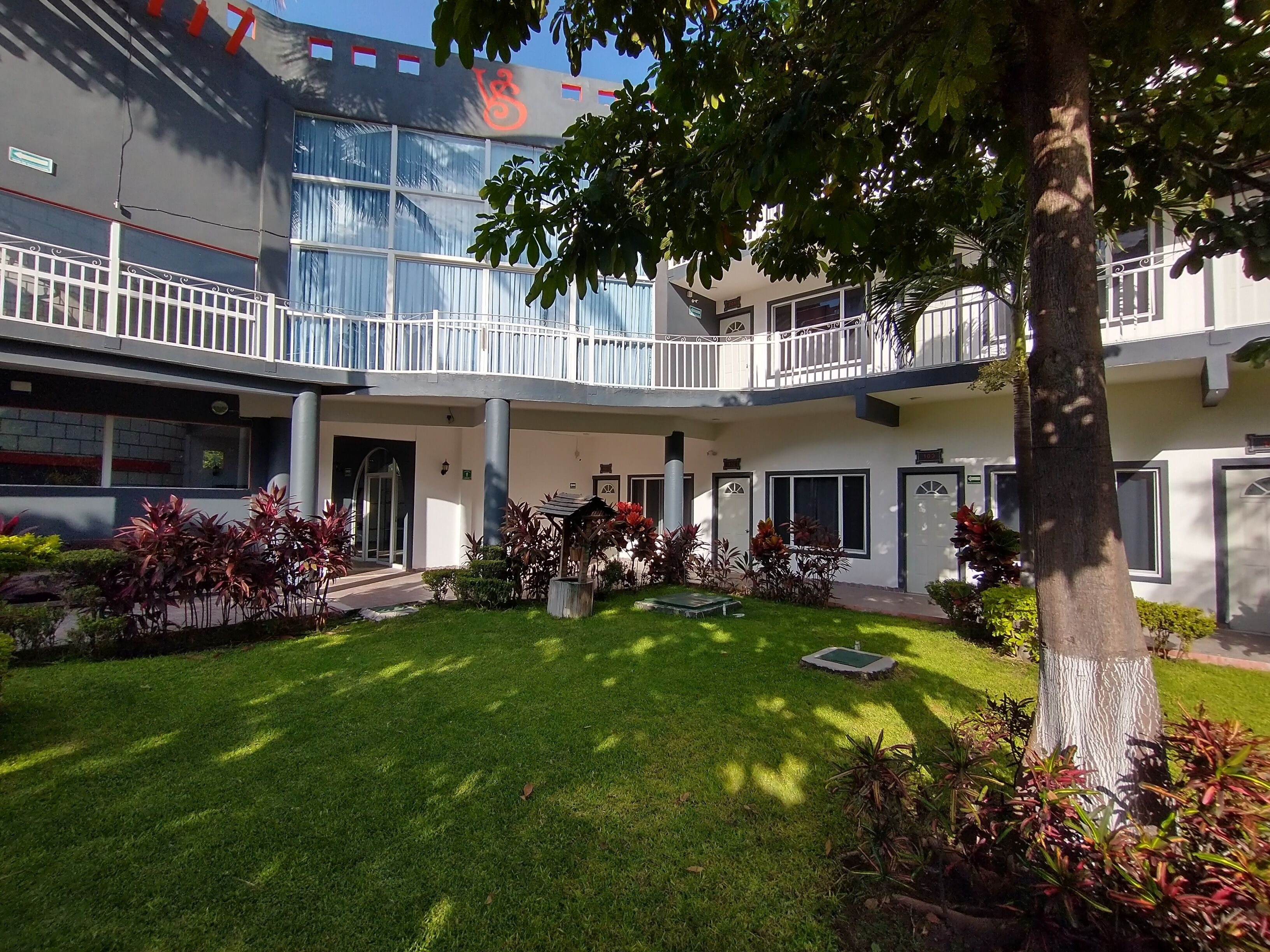 Un hotel con patio interior, varios balcones y una diversidad de plantas.