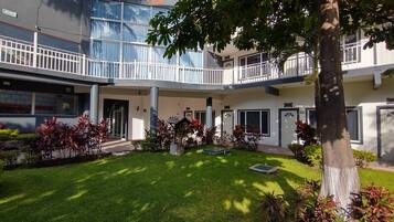 Un hotel con patio interior, varios balcones y una diversidad de plantas.