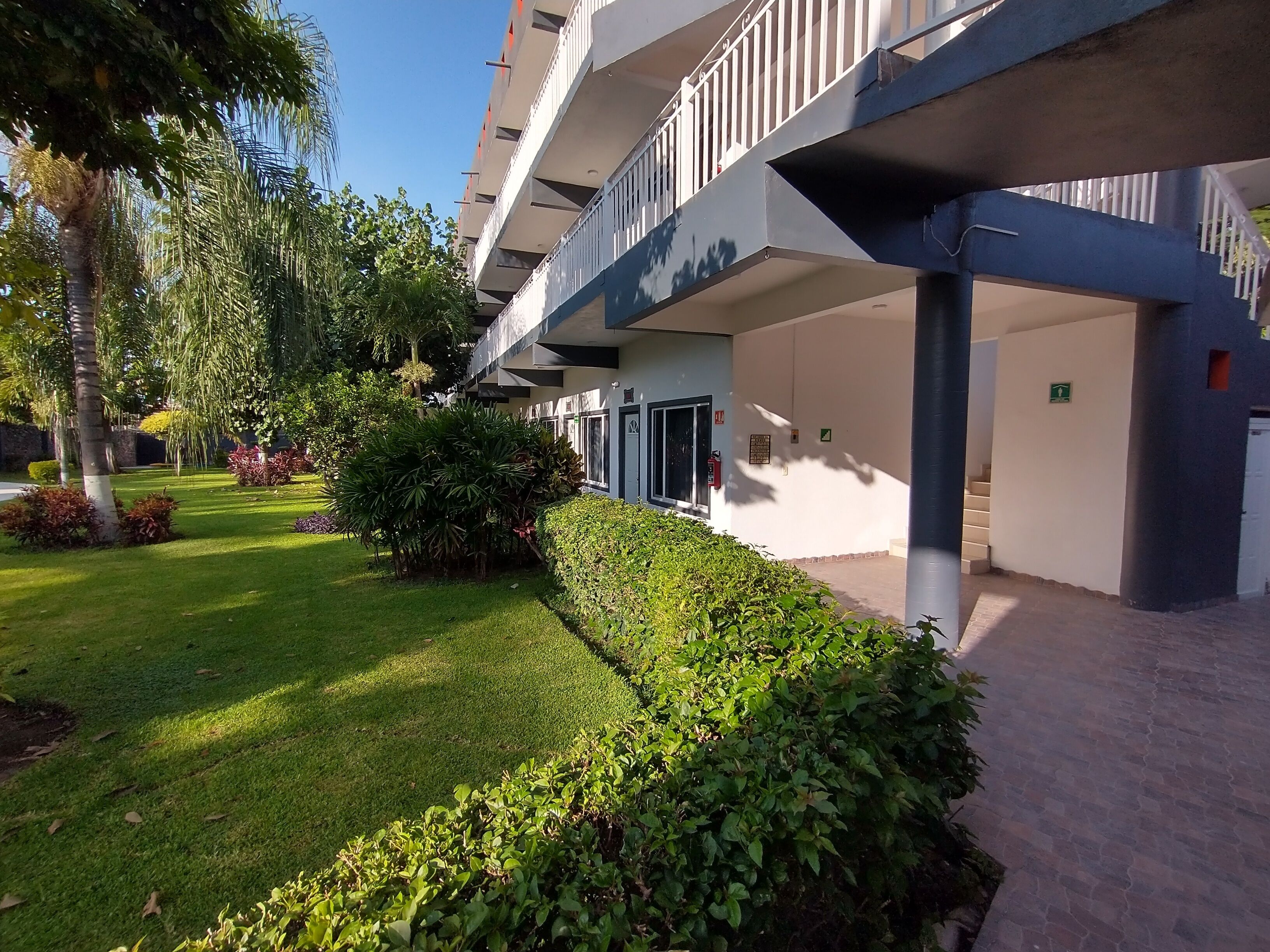 A multi-story building with balconies, a well-maintained lawn, and a clear sky.