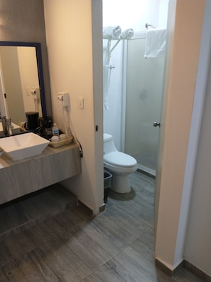 Un baño con lavamanos, espejo y zona de ducha.