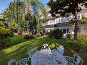A well-maintained outdoor area with a lawn, seating, and a building with balconies. - Villa Salvatore (Xochitepec)