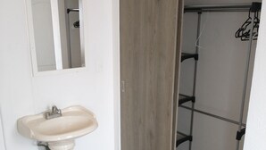 A bathroom with a pedestal sink, a mirror, a wooden door, and a shower area. - Villa Salvatore (Xochitepec)