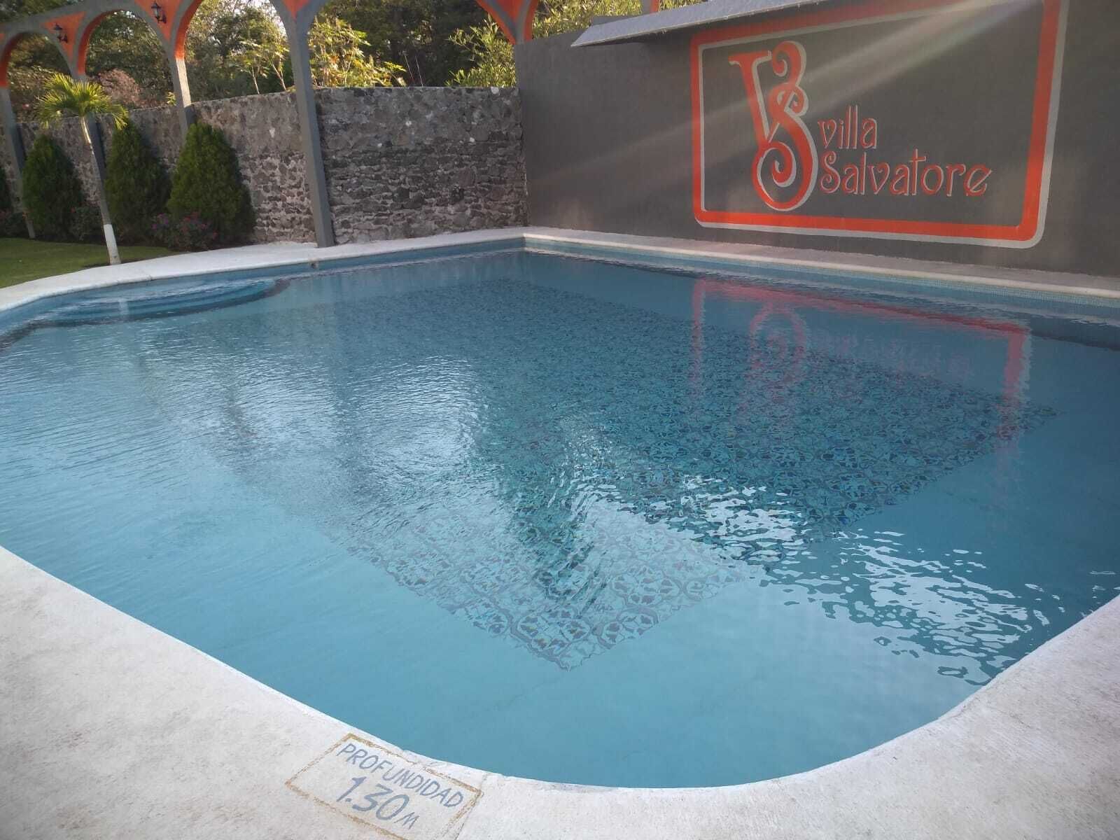 Una piscina con una profundidad de 1,30 metros, rodeada por un muro de piedra y un arco decorativo.