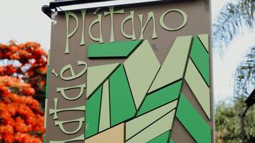 Un letrero con el nombre 'Platano' y algo de texto en un idioma extranjero.