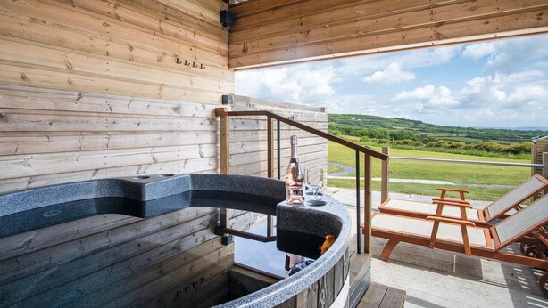 A wooden interior with a hot tub, a wooden staircase, and a view of a green landscape. - Paviland - Safari Glamping Tent - Llangennith (Llangennith)