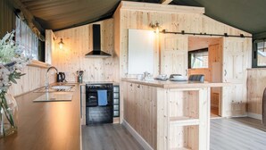A wooden interior with a kitchen area featuring a stove, oven, and wooden cabinets. - Paviland - Safari Glamping Tent - Llangennith (Llangennith)