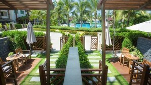 A covered outdoor area with a pool, wooden furniture, and palm trees. - Longxing Lehman Sea View Resort (Sanya)