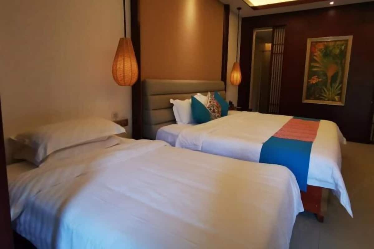 Quarto de hotel com duas camas, cabeceira e um quadro na parede.