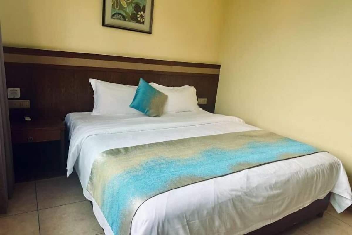 Quarto de hotel com cama, mesa de cabeceira e um quadro na parede.