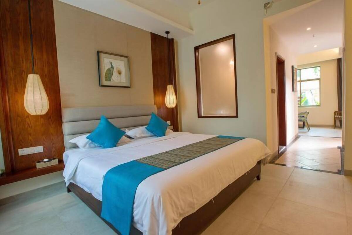 Quarto de hotel com uma cama grande, painéis de madeira, uma obra de arte emoldurada na parede e vista para o corredor.