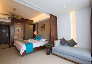 Una habitación de hotel moderna con una cama, un sofá, un ventilador de techo y un televisor montado en la pared.