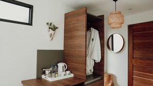 A modern bathroom with a wooden vanity, a hanging plant, a mirror, and a wooden door. - Mata e' Platano Guesthouse #6, Luquillo PR (Luquillo)