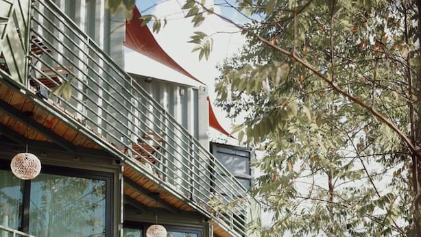Un bâtiment moderne doté d’un balcon, de grandes fenêtres et d’un jardin bien entretenu.