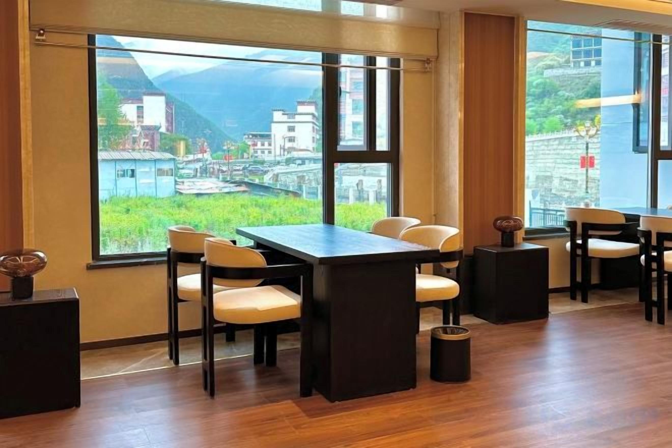 A conference room with a large table and chairs, large windows with a view of a cityscape and mountains.