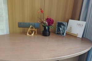 Un escritorio de madera con un florero, una cámara negra y dos cuadros enmarcados.