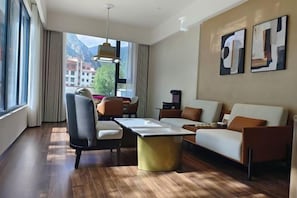 A hotel room with a dining area, a sofa, and a view of mountains.