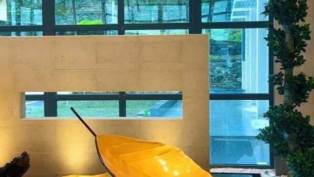 A room with a large window, a concrete partition, and a yellow chair.