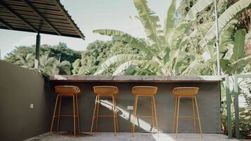 A patio area with four wooden bar stools and a concrete counter.