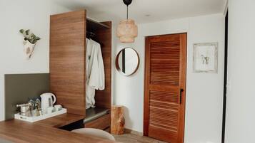 Una habitación moderna con un armario de madera, un espejo redondo, una puerta de madera y un taburete pequeño de madera.