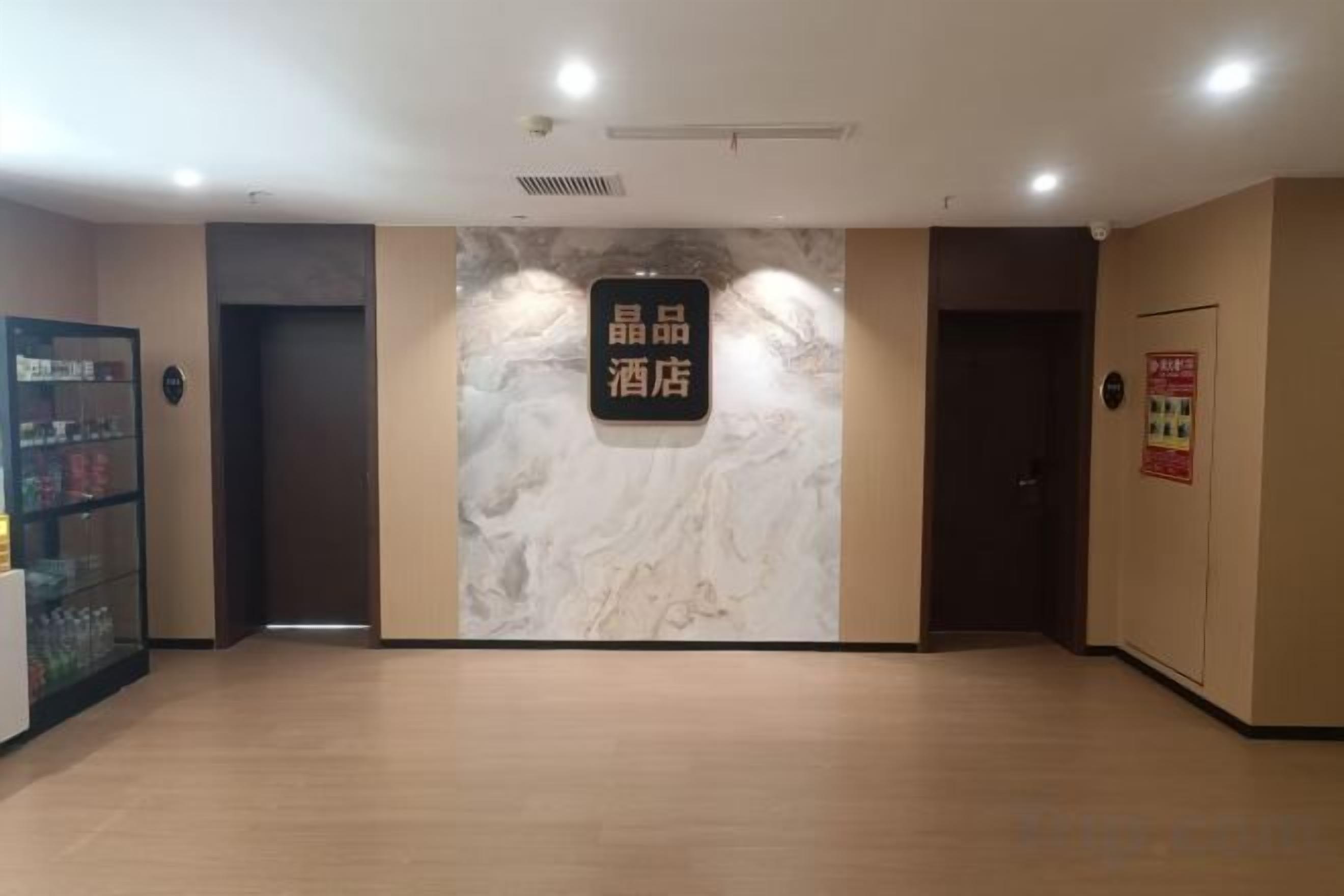 A hotel lobby with a marble wall, a reception desk, and a vending machine.