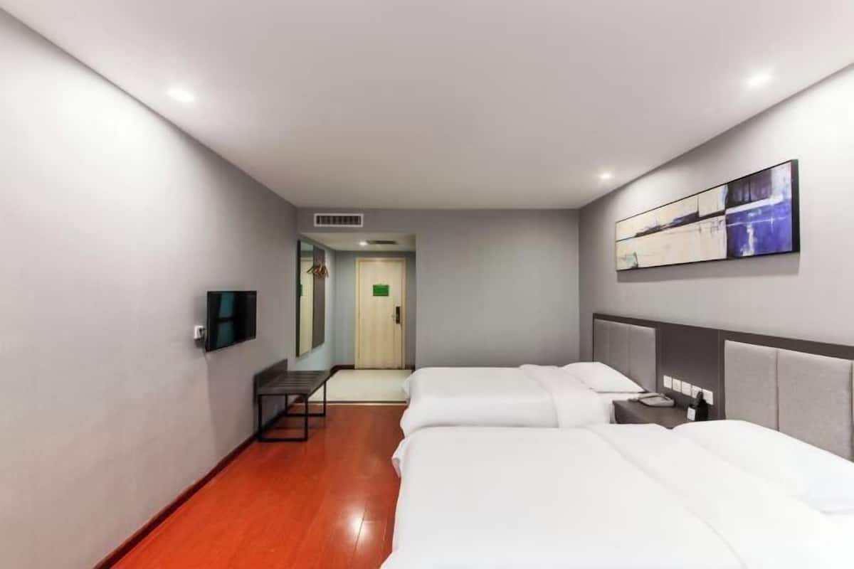 Quarto de hotel com duas camas, uma escrivaninha, televisão e um quadro na parede.