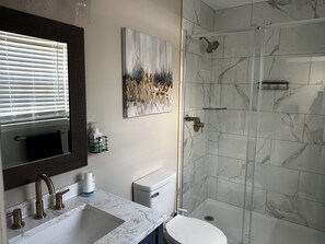 Ein Badezimmer mit Marmorwaschbecken, Toilette und einer Duschkabine mit Handbrause.