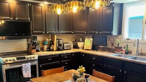 Una cocina moderna con armarios oscuros, electrodomésticos de acero inoxidable y una mesa de comedor de madera.