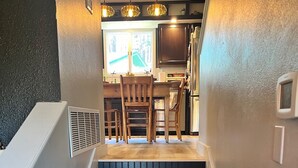 Una escalera conduce a una zona de cocina con escalones de madera, una mesa de comedor y sillas.