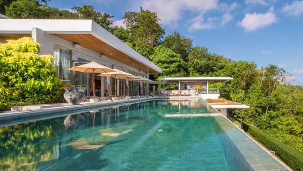 Ein moderner Poolbereich mit klarem Pool, Liegestühlen und Sonnenschirmen.