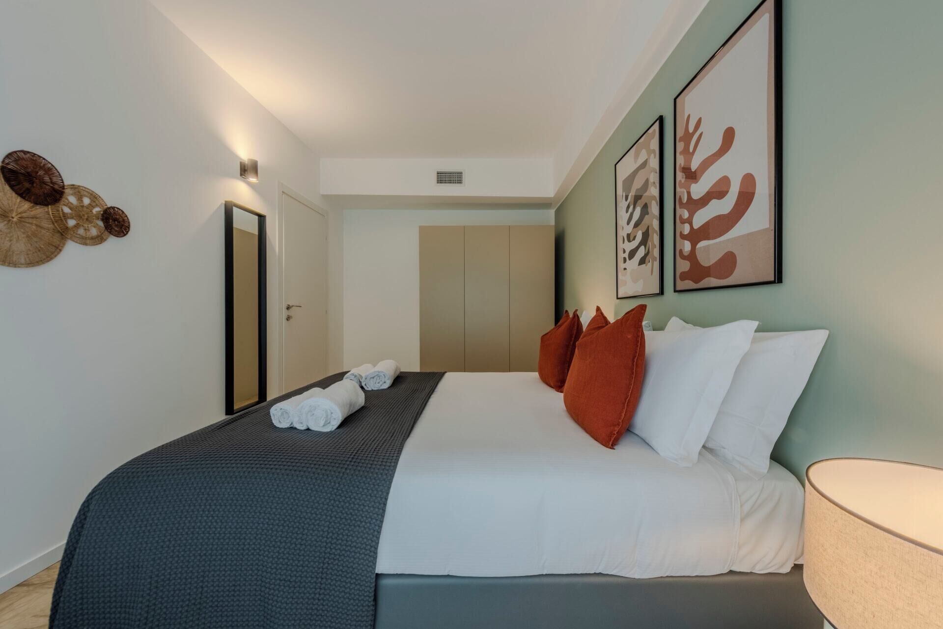 A hotel room with a bed, a nightstand, a lamp, and artwork on the wall.