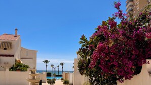 Un patio con una fuente, plantas en macetas y vista al mar.