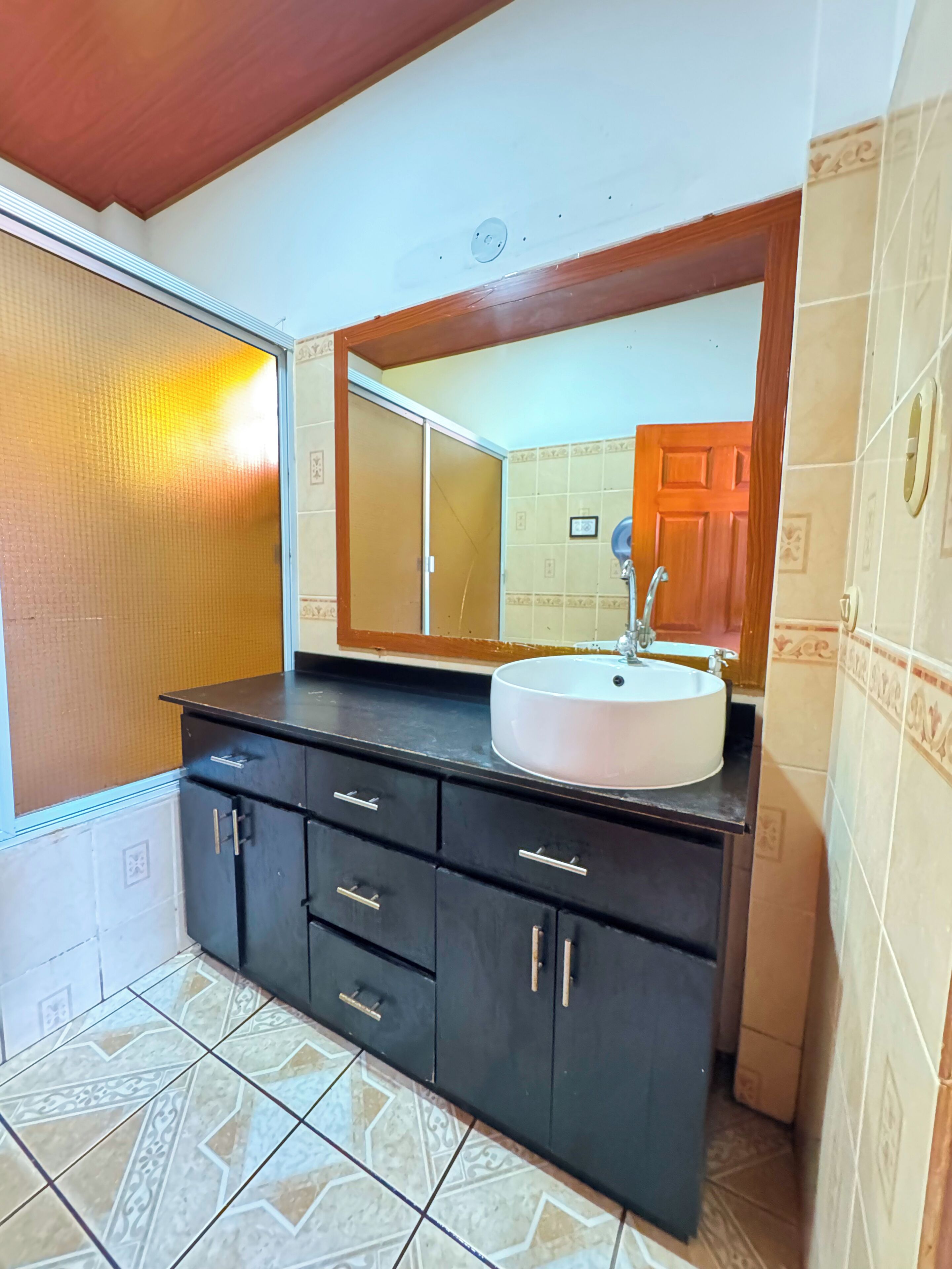 A bathroom with a black vanity, a white sink, and a large mirror.