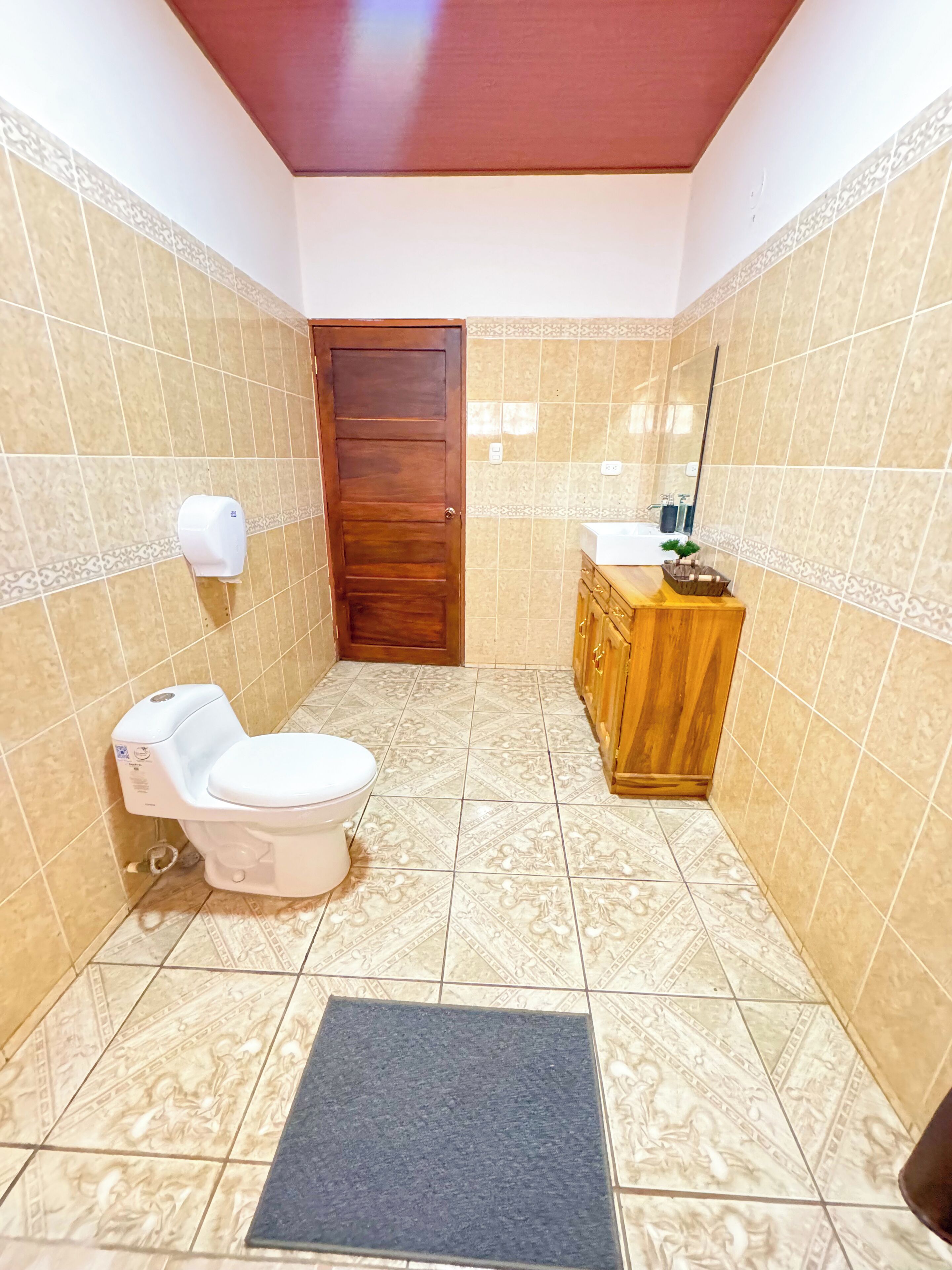 A bathroom with a toilet, sink, and wooden cabinet.