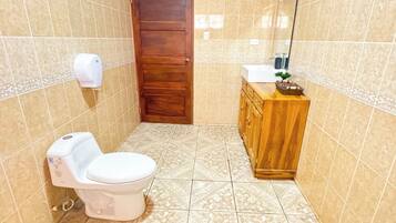 A bathroom with a toilet, sink, and wooden cabinet.