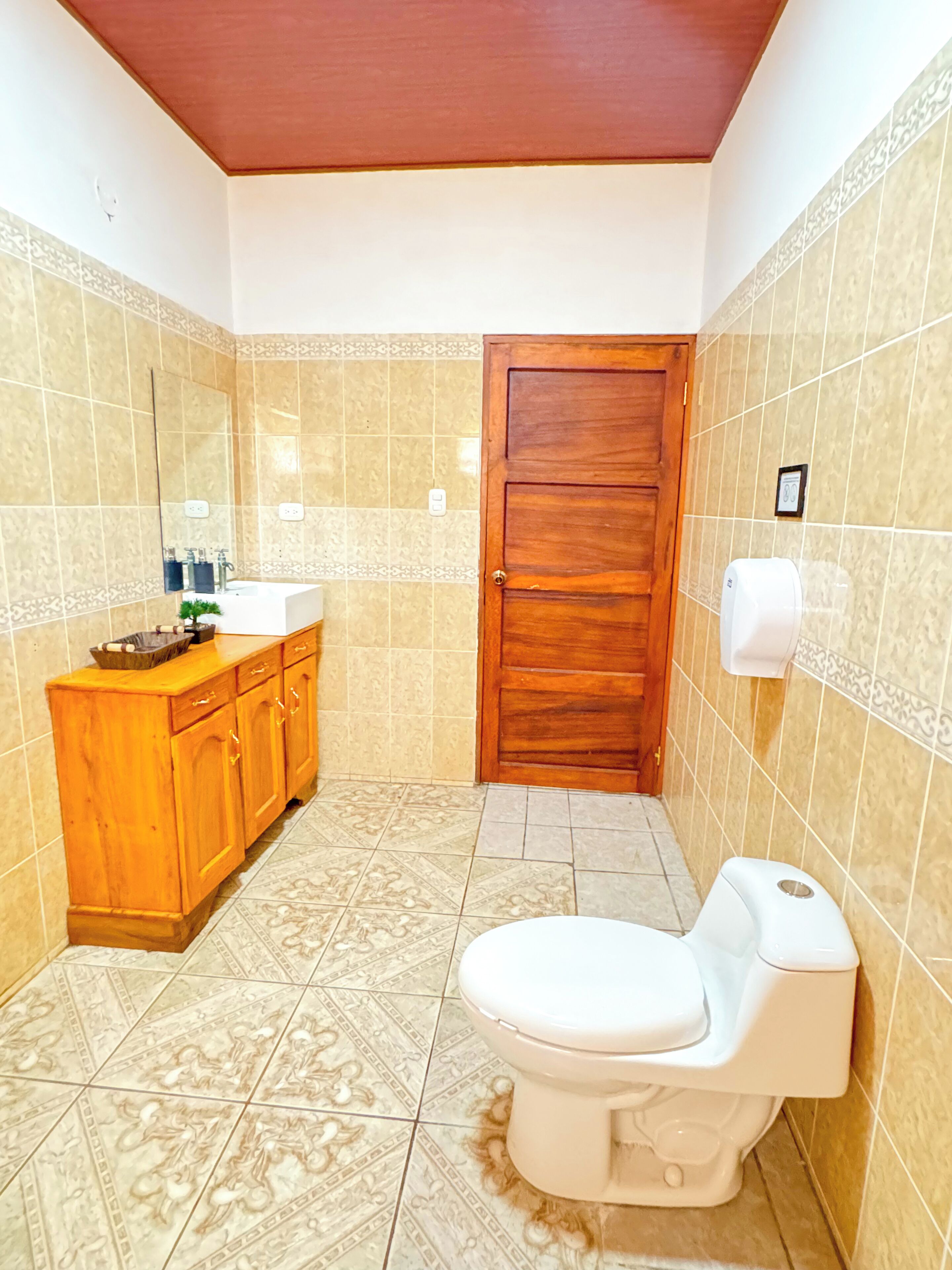 A bathroom with a wooden cabinet, a white toilet, and patterned tiles.