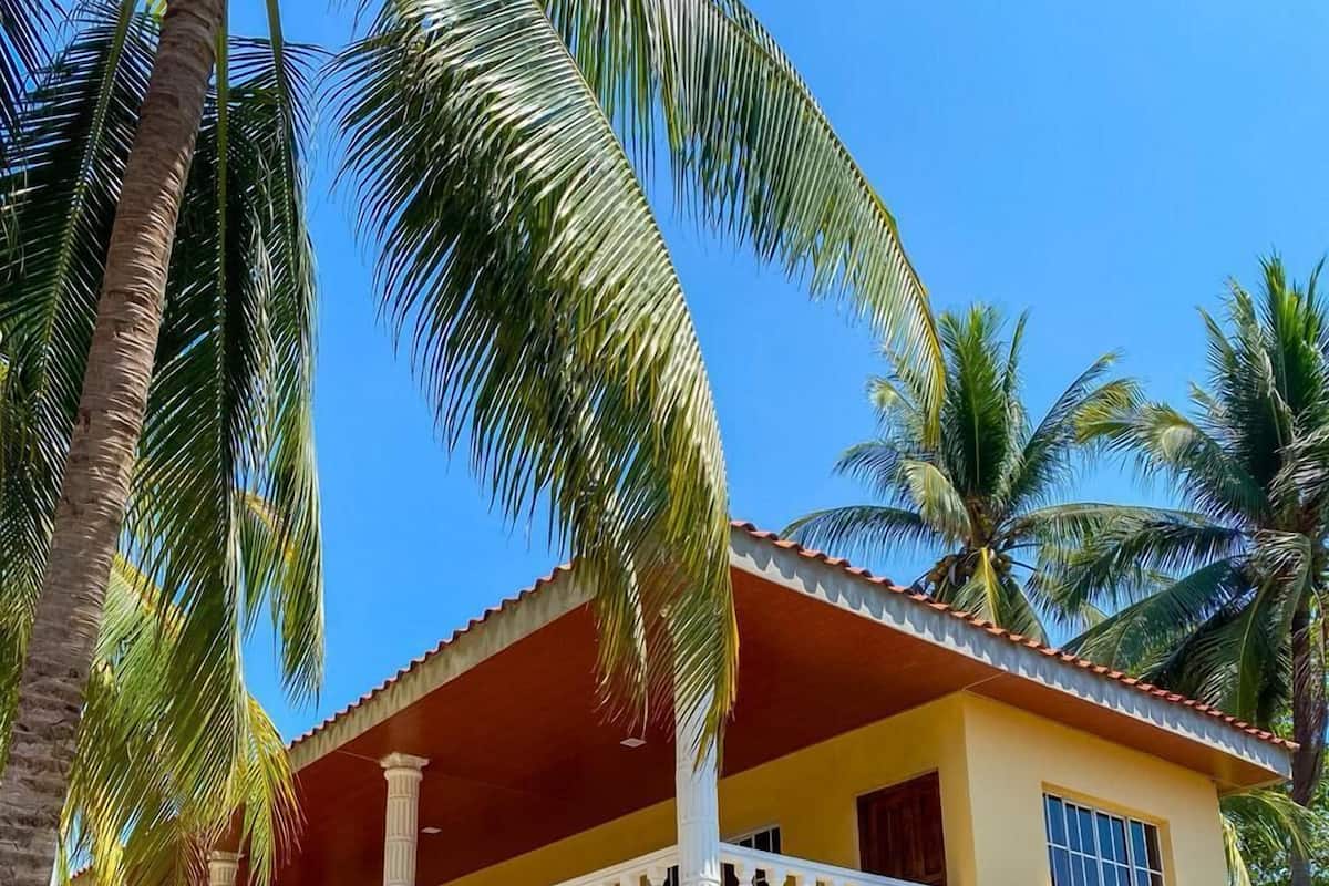 A two-story building with a balcony, columns, and a yellow facade.