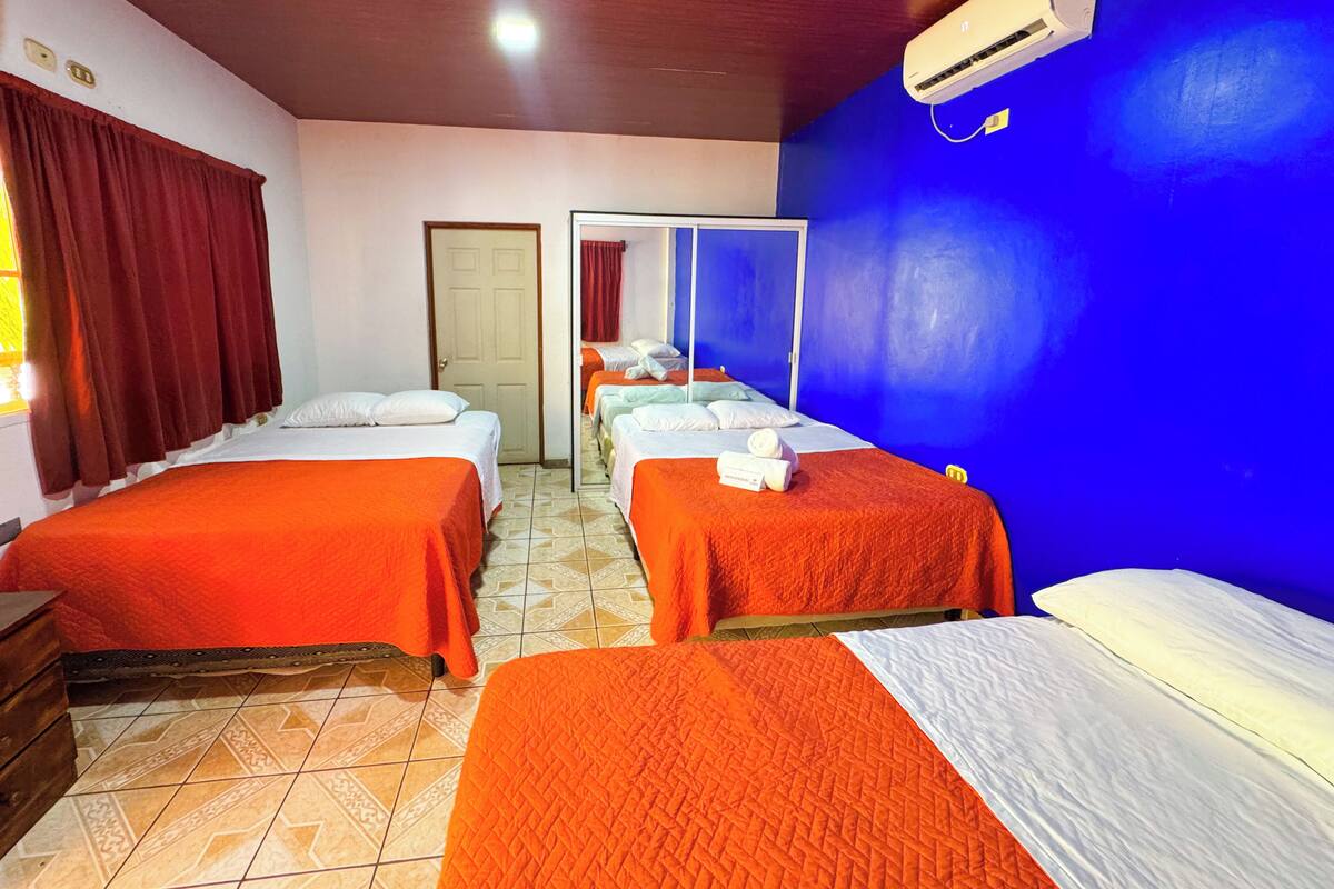 A hotel room with two beds, a wardrobe, a mirror, and a ceiling fan.