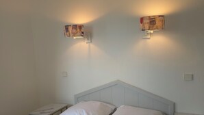 A hotel room with a bed, two bedside tables, and two wall-mounted lamps. - Les rives des Issambres 1201 (Roquebrune-sur-Argens)