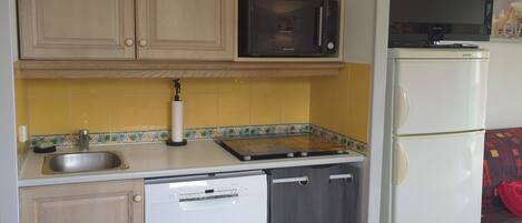 A compact kitchen with a microwave, stove, and refrigerator.