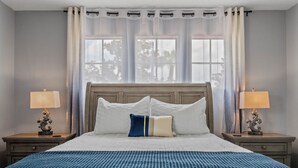 A neatly arranged hotel room with a large bed, two bedside tables with lamps, and a view of trees through the window. - Luxury relaxing stay. A brand new remodel villa near Disney and Legoland  (Haines City)